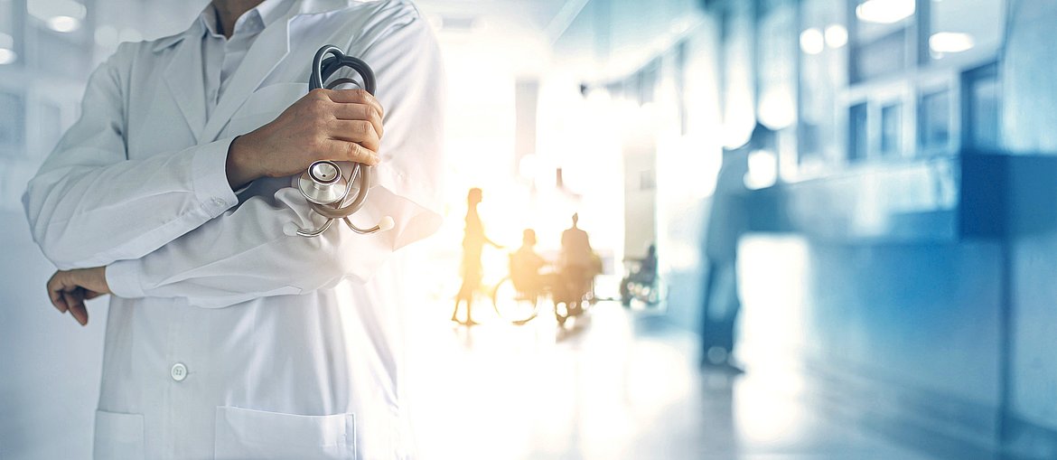 Arzt mit Stethoskop steht in Krankenhaus