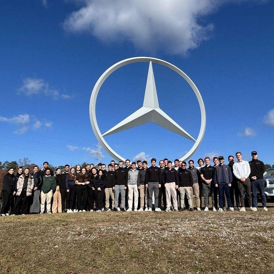 Eine Gruppe von international Studierenden mit den U.S. Co-Ops vor einem großen Mercedes Benz Stern