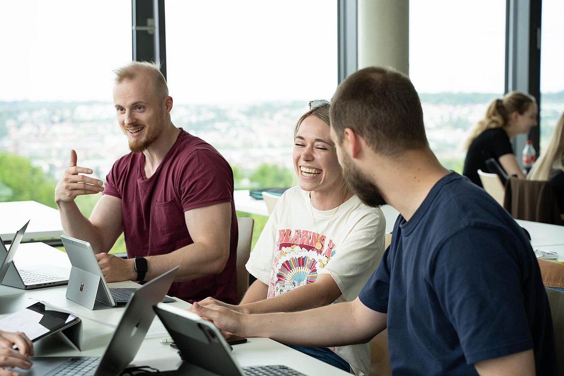 Drei Studierende lernen gemeinsam in der Gruppe und lachen