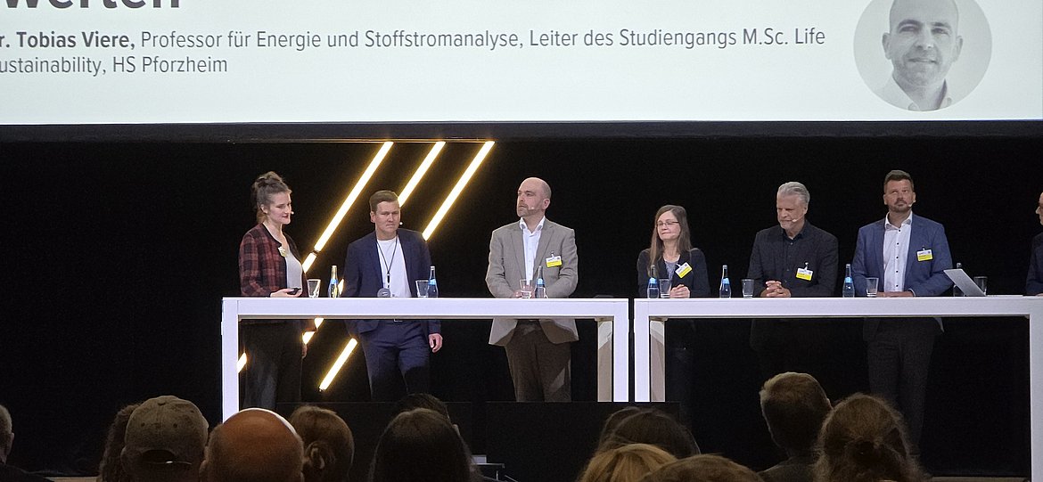 Sechs Personen an einem Stehtisch auf einer Bühne