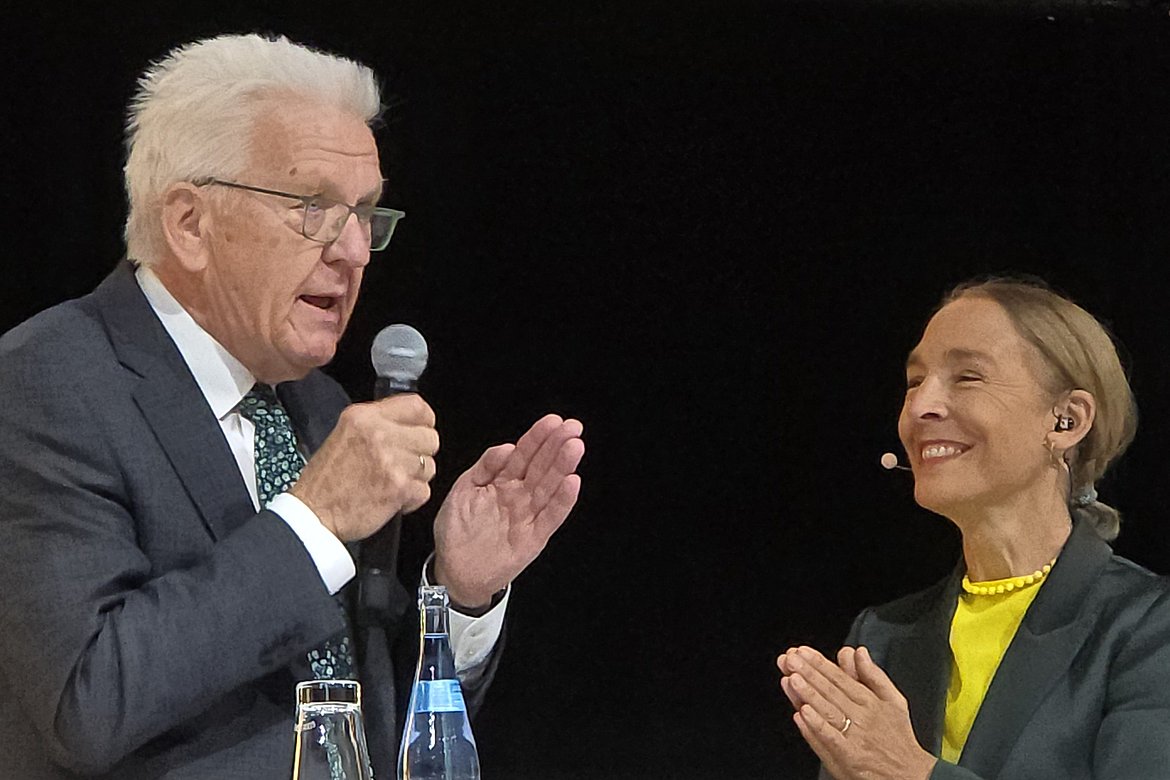 Ministerpräsident Winfried Kretschmann mit Mikrofon mit Moderatorin Andrea Thilo