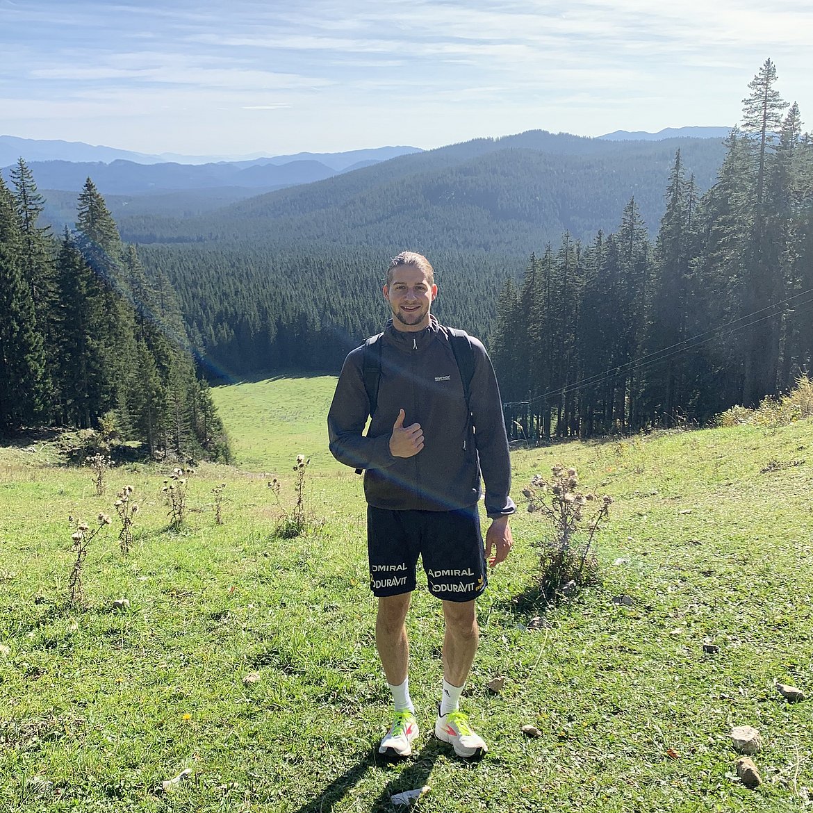Nick Kusch auf Wiese in Berglandschaft bei Sonnenschein