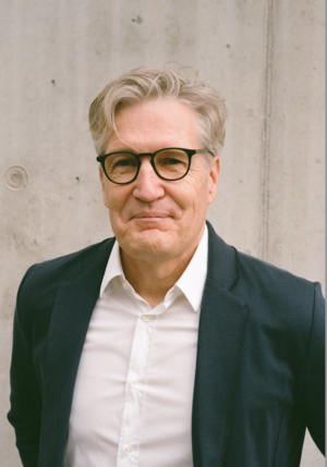 Älterer Herr mit grauem Haar und Brille lächelt in die Kamera