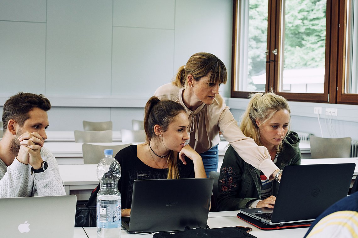Prof. Dr. Yasmin Merz, Professorin für Media Management und Digital Media, erklärt ein Konzept und deutet dabei auf den Laptop einer Studierenden