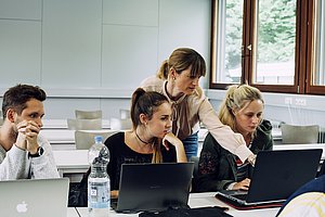Prof. Dr. Yasmin Merz zeigt auf den Laptop einer Studierenden und erklärt