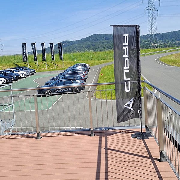 Ausstellung von Autos im Freien mit mehreren Fahrzeugen, dahinter sanfte Hügel in der Landschaft