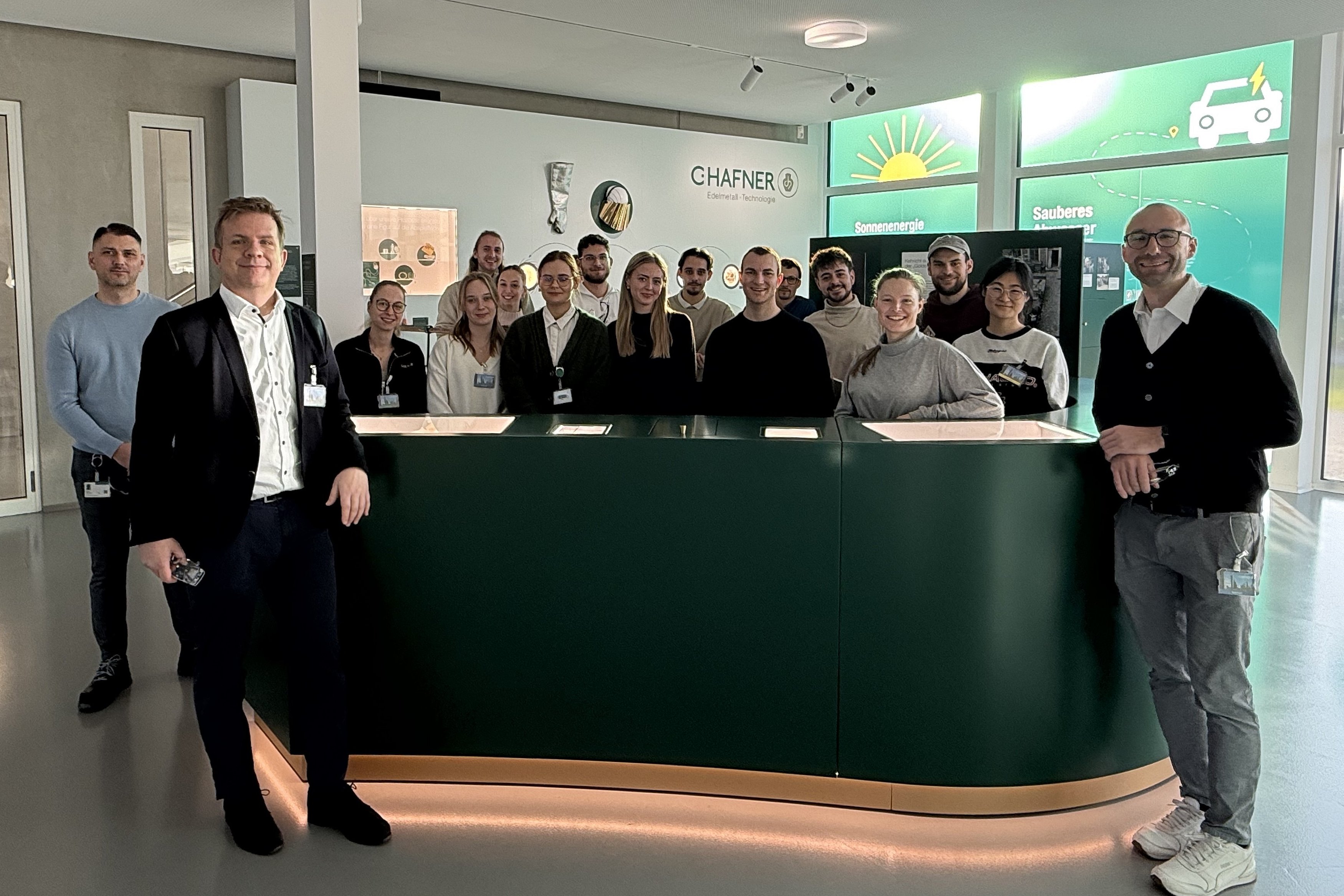 Gruppenfoto von Personen stehend vor und hinter einem Ausstellungsmöbel
