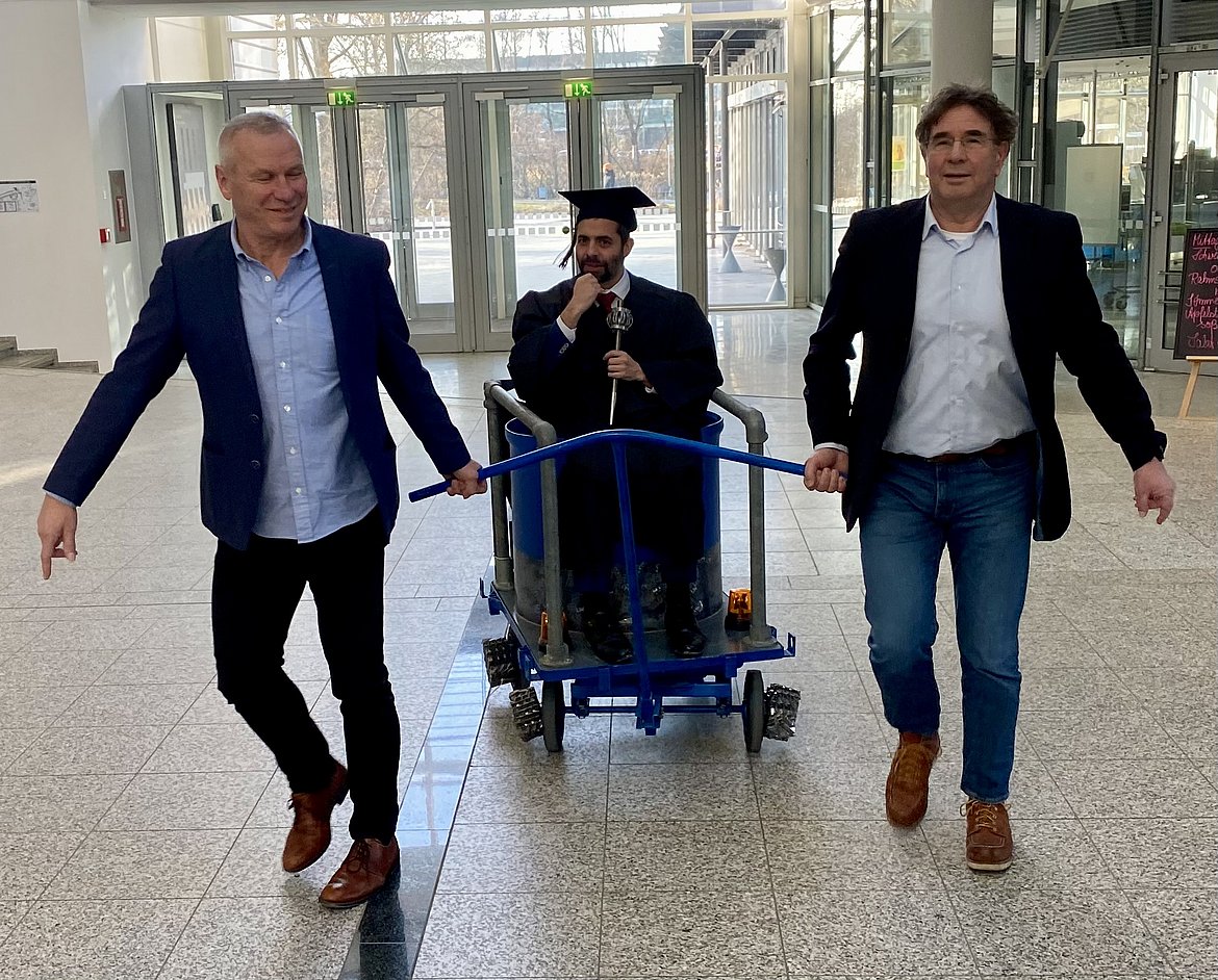 Eloy Melian wird von seinen beiden Doktorvätern durch die TU München gezogen.