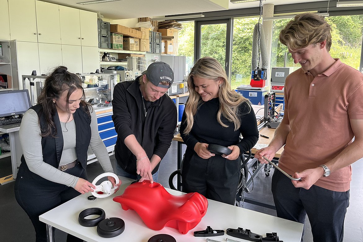 Vier Personen, die sich über ein zerlegtes Bobby Car beugen