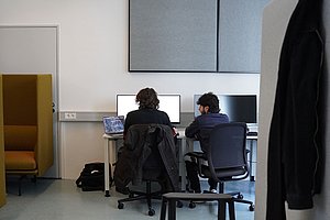 Zwei Studierende arbeiten gemeinsam an einem Laptop in einem kollaborativen Lernraum