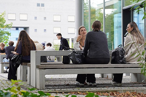 Students are enjoying a relaxed summer day on campus in front of the library
