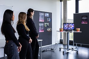 Studierende präsentieren in einer Vernissage ihr Ergebnis zum Thema KI & Kreativität. Hier: Wie könnte eine Welt aussehen, auf der wir 100 Jahre überbrücken, damit unsere Welt sich regenerieren kann? 