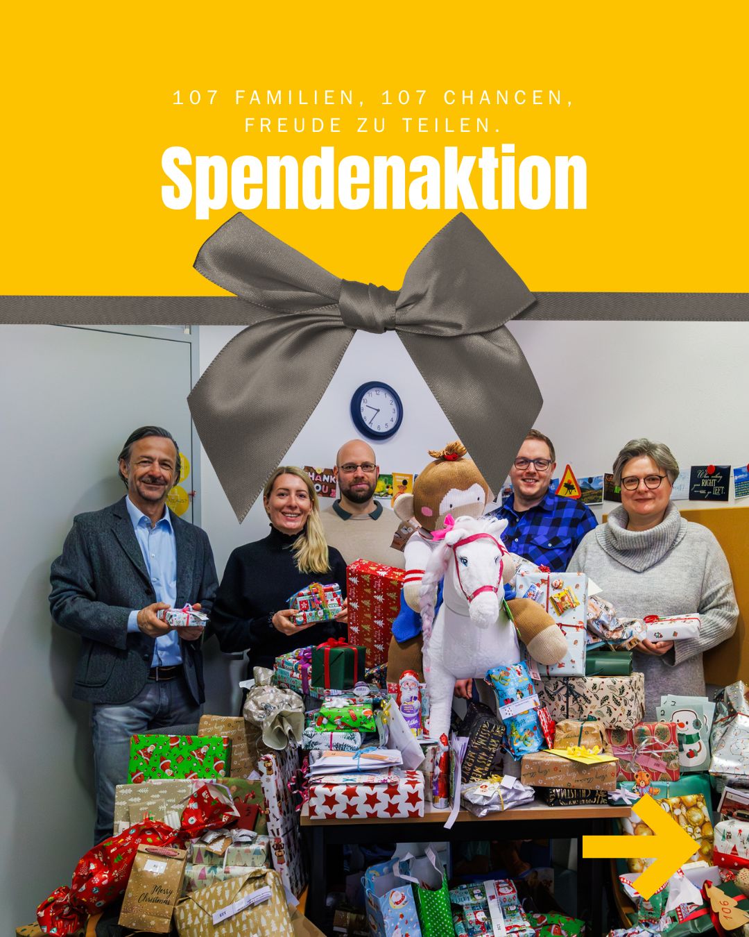 Beteiligte der Spendenaktion für Profamilia lächeln hinter einem Berg von gesammelten Geschenken.
