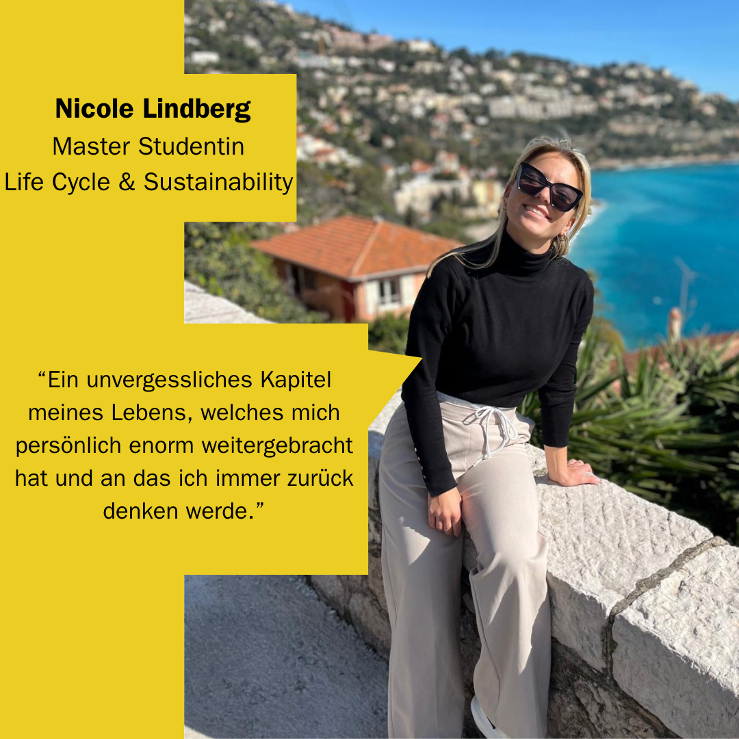 Nicole Lindberg halb auf Mauer sitzend mit Häusern auf bergigem Küstenabschnitt im Hintergrund